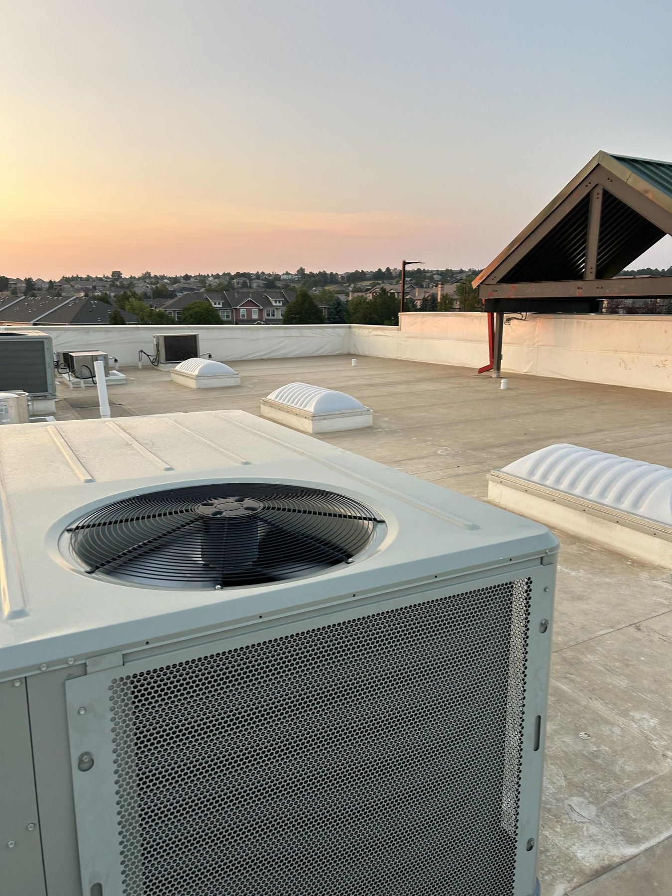 Rooftop packaged HVAC unit at dusk above a Denver metro neighborhood