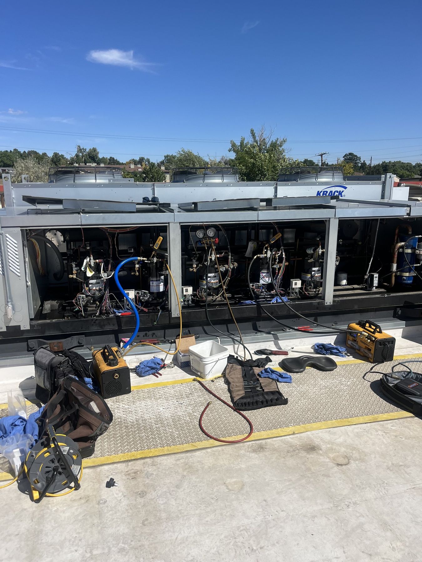 SRV technicians' tools and gauges laid out at an open parallel refrigeration rack on a rooftop in Lakewood, Colorado
