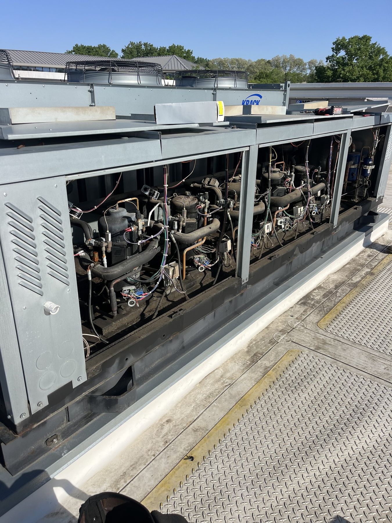 Open parallel refrigeration rack with compressors and controls exposed on a rooftop in the Des Moines metro