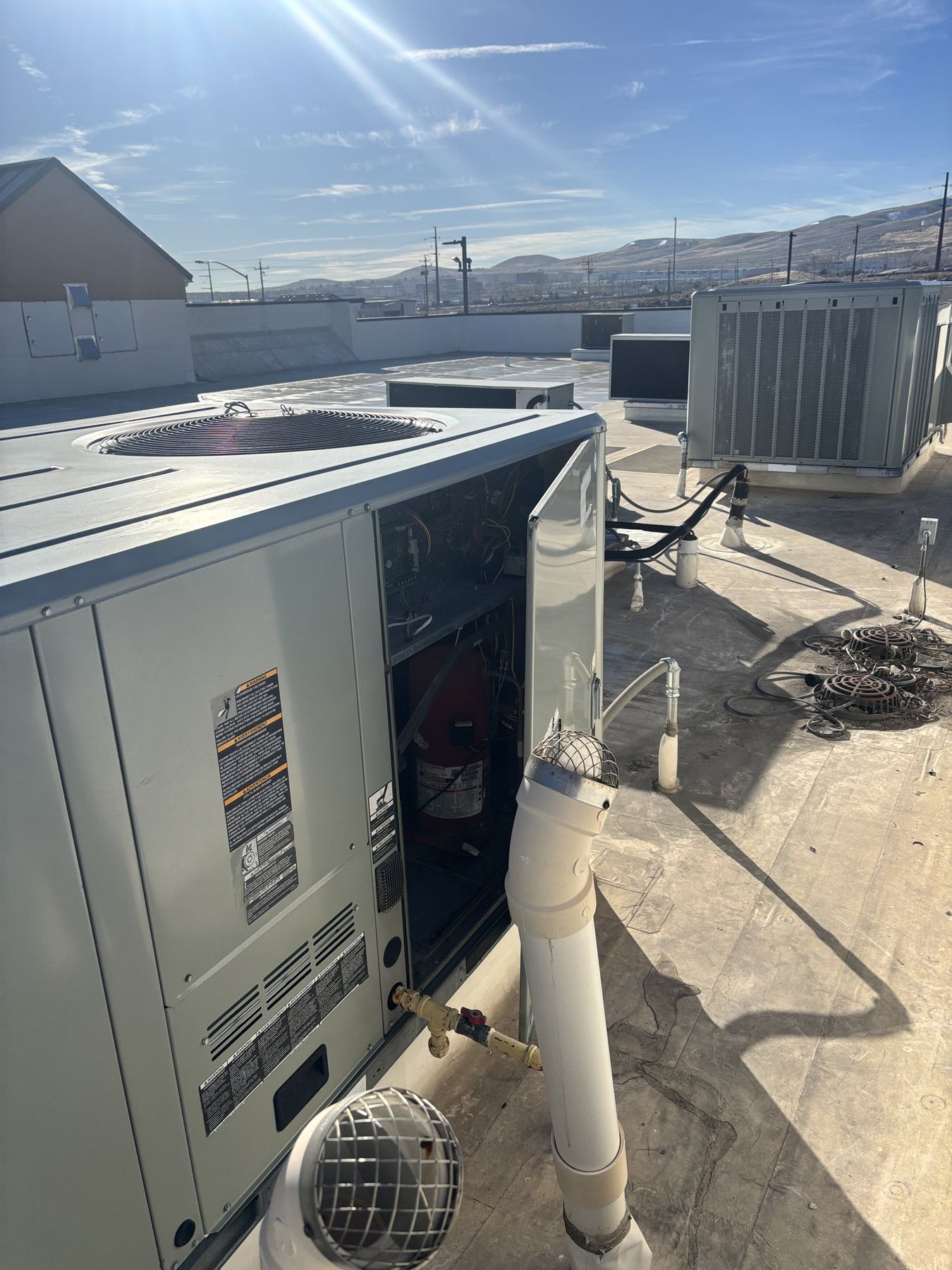 Rooftop packaged HVAC units under service with the Reno-area hills and high desert on the horizon