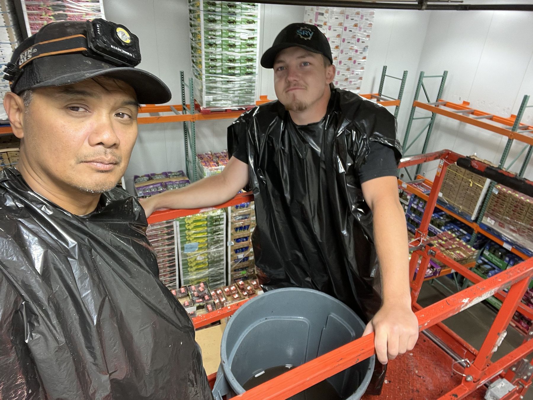 Two SRV technicians in a customer's walk-in produce cooler during a field service call, one wearing an SRV cap